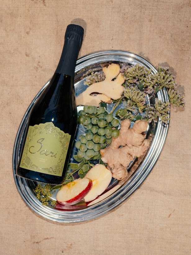 Bottle of Sari Red laid on a plate with sour cherries, figs and dark fruit